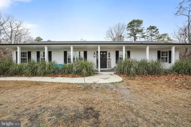 front view of house with potted plants and a yard
