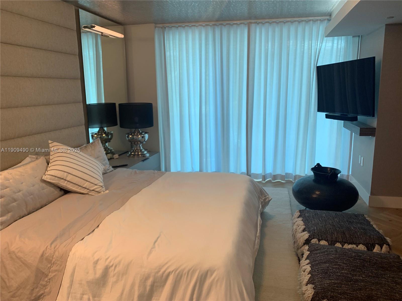 9401 Collins Avenue, Unit 305 Surfside, FL 33154 - Photo 11 of 17 a bedroom with a bed and a flat screen tv