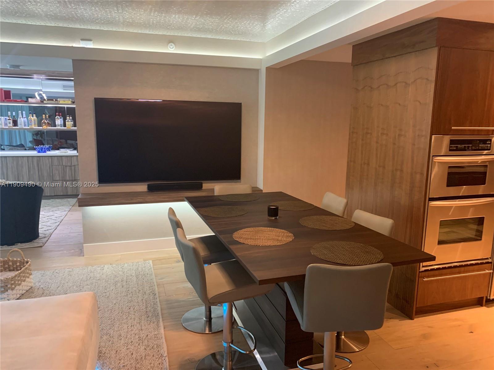 9401 Collins Avenue, Unit 305 Surfside, FL 33154 - Photo 6 of 17 a living room with furniture a flat screen tv and a table