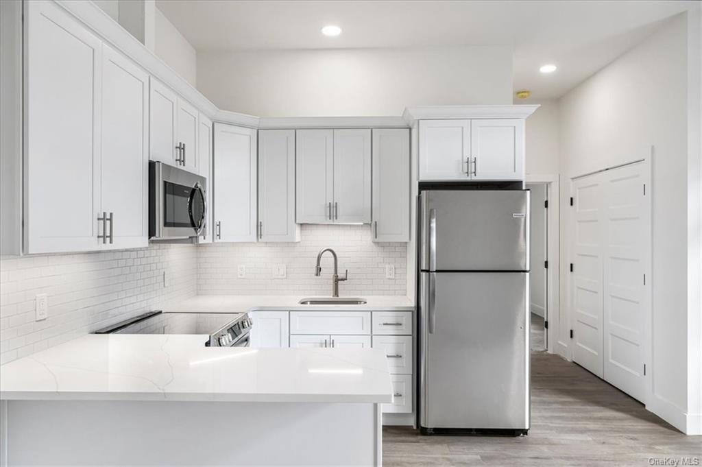 a kitchen with stainless steel appliances granite countertop a refrigerator sink and white cabinets