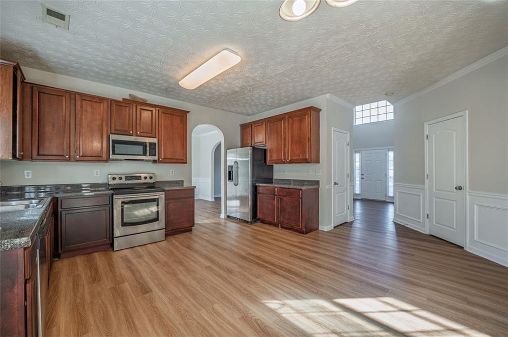 3017 Bellingham Way Lithia Springs, GA 30122 - Photo 8 of 44 a kitchen with stainless steel appliances wooden floors and wooden cabinets