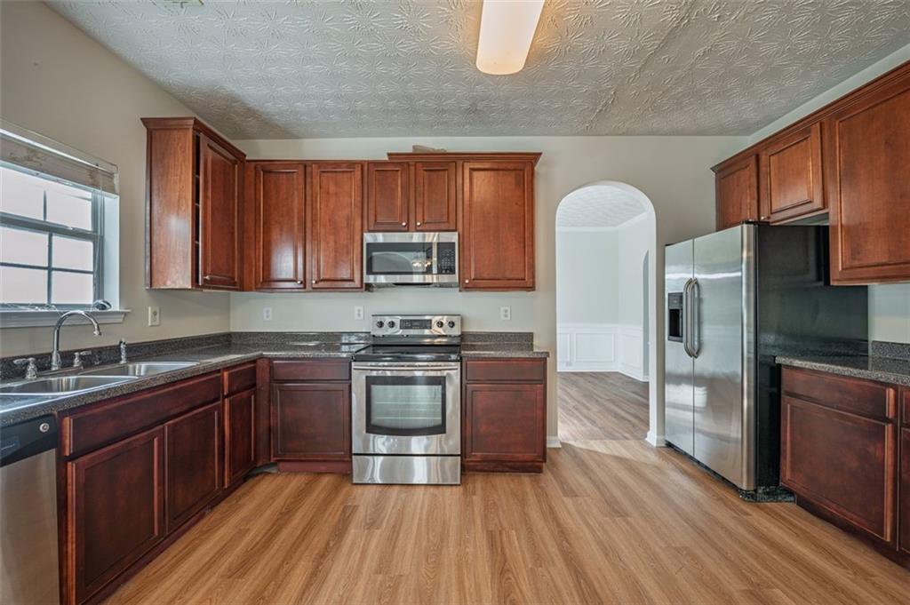 3017 Bellingham Way Lithia Springs, GA 30122 - Photo 9 of 44 a kitchen with stainless steel appliances granite countertop a stove a sink dishwasher a refrigerator and a microwave oven with wooden floor