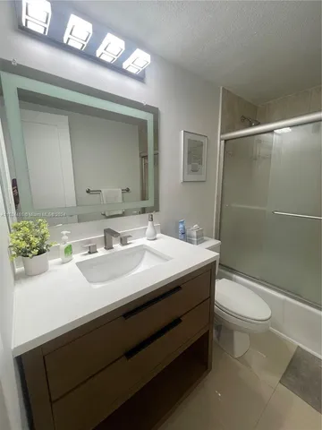 a bathroom with a sink a toilet a mirror and shower
