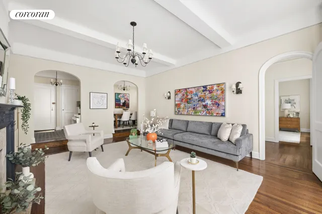 a living room with furniture a chandelier and wooden floor