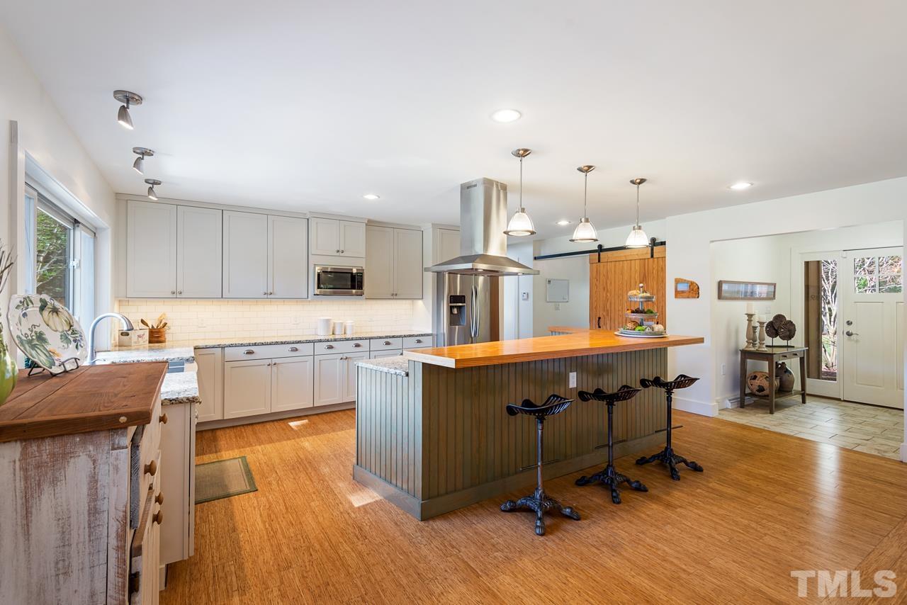 2639 Umstead Road Durham, NC 27712 - Photo 16 of 42 a kitchen with stainless steel appliances kitchen island hardwood floor sink stove refrigerator and cabinets
