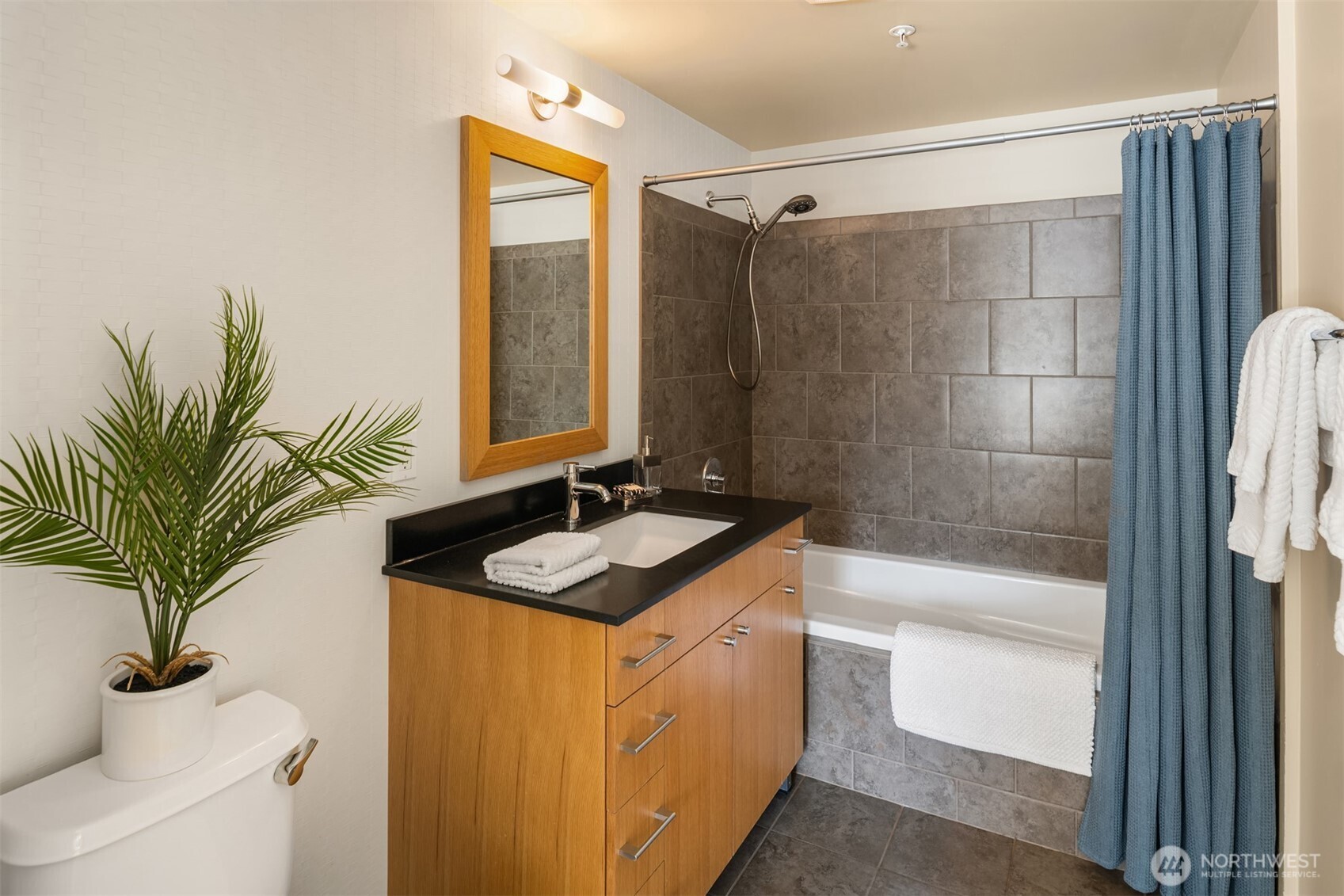 76 Cedar Street, Unit 609 Seattle, WA 98121 - Photo 18 of 31 a bathroom with a granite countertop sink a mirror a vanity and a shower