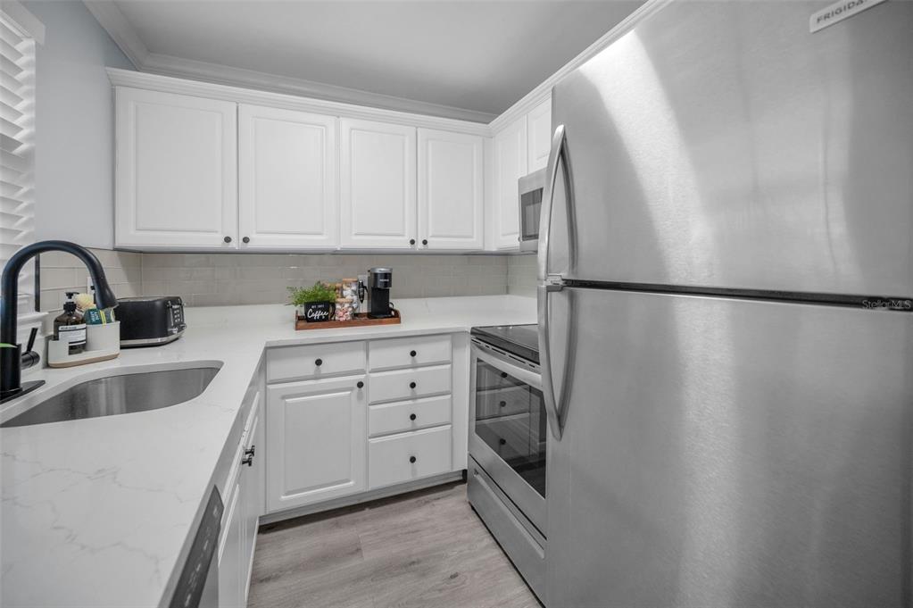 19417 Gulf Boulevard, Unit F207 Indian Rocks Beach, FL 33785 - Photo 12 of 56 a kitchen with appliances a sink and cabinets
