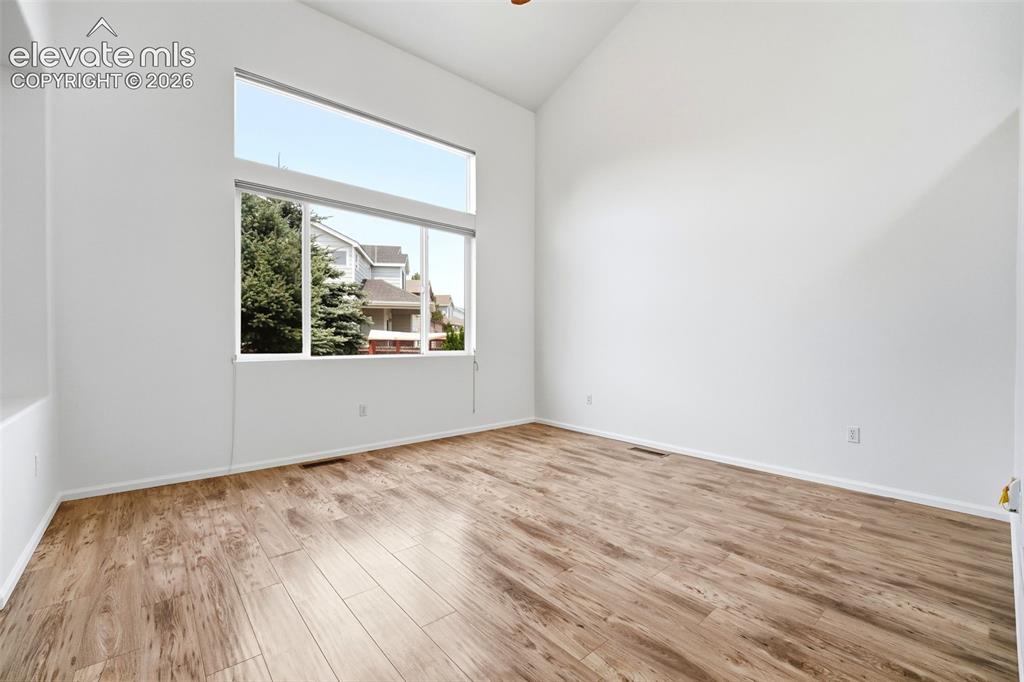 7904 Coffee Road Peyton, CO 80831 - Photo 3 of 48 Spacious room featuring vaulted ceilings, expansive window array, wood-finish flooring, and white baseboards