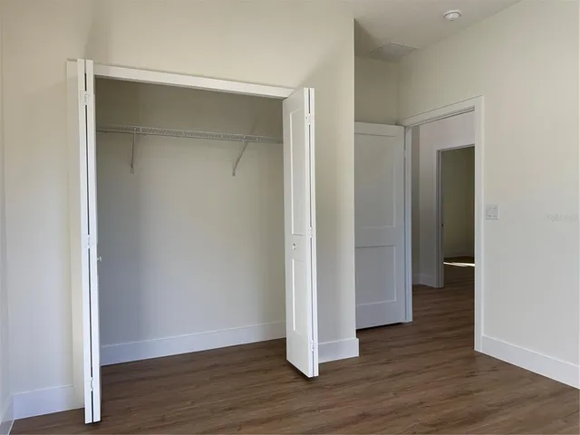 an empty room with wooden floor & closet