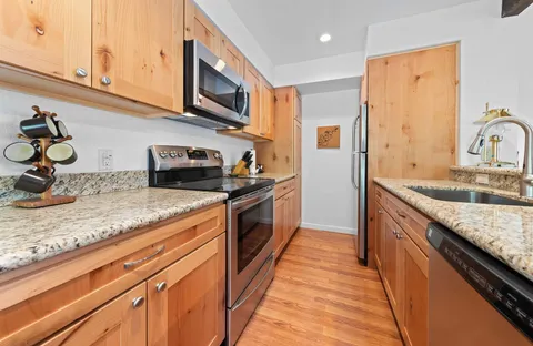 a kitchen with stainless steel appliances granite countertop a sink stove and refrigerator