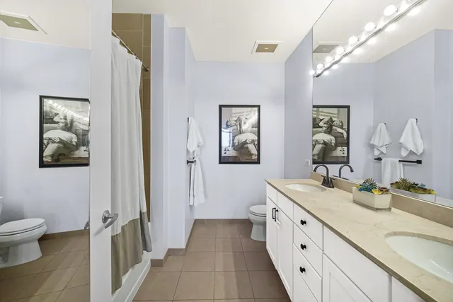 a spacious bathroom with a double vanity sink a mirror and a toilet