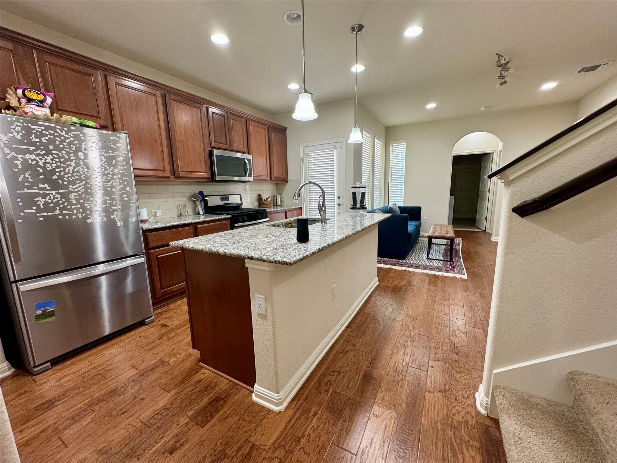 5904 Baythorne Drive Austin, TX 78747 - Photo 6 of 24 Kitchen featuring stainless steel appliances, arched walkways, decorative light fixtures, light stone countertops, and dark wood-style floors