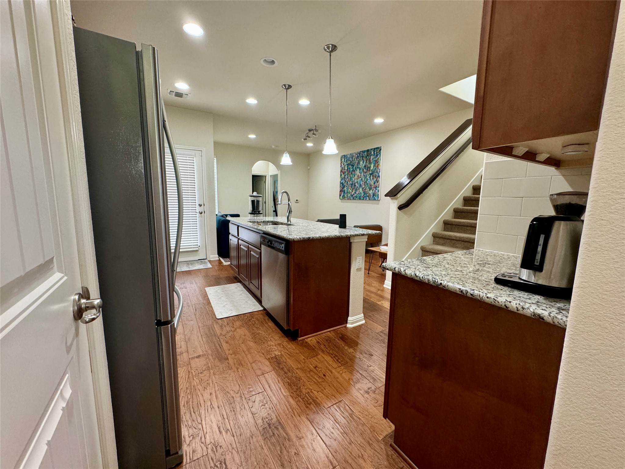 5904 Baythorne Drive Austin, TX 78747 - Photo 7 of 24 Kitchen featuring pendant lighting, stainless steel appliances, a center island with sink, dark wood finished floors, and light stone countertops