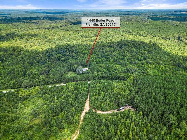 a view of a field with a lush green forest