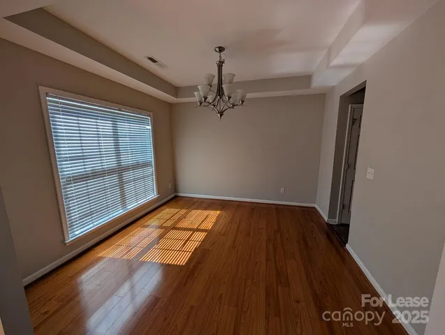 a view of a room with wooden floor a ceiling fan and windows