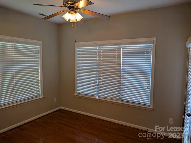 a view of an empty room with a window and wooden floor