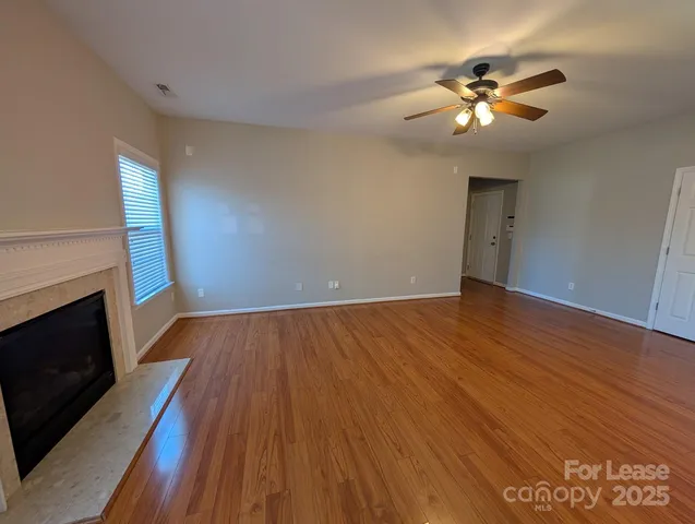 a view of an empty room with wooden floor and a fireplace