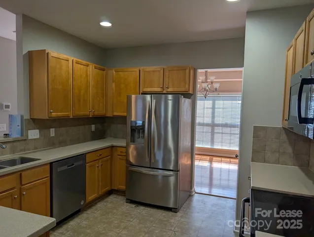 a kitchen with stainless steel appliances granite countertop a refrigerator a sink a stove with wooden cabinets