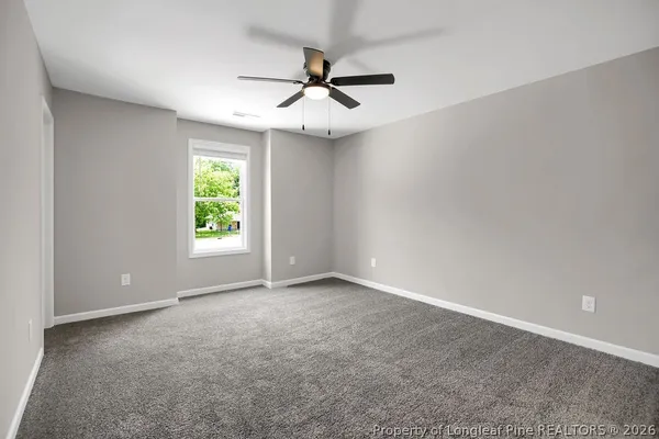 an empty room with windows and fan