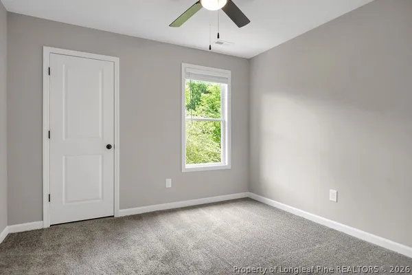 an empty room with a window and a chandelier fan