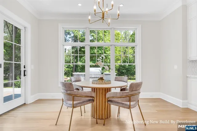 a dining room with wooden floor a chandelier a glass table and chairs