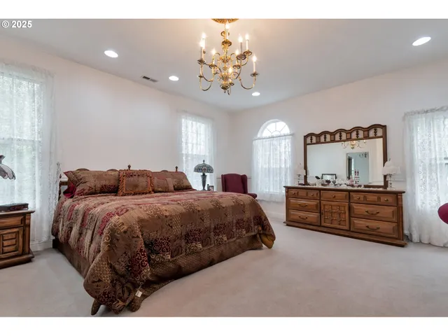 a spacious bedroom with a bed chandelier and a window