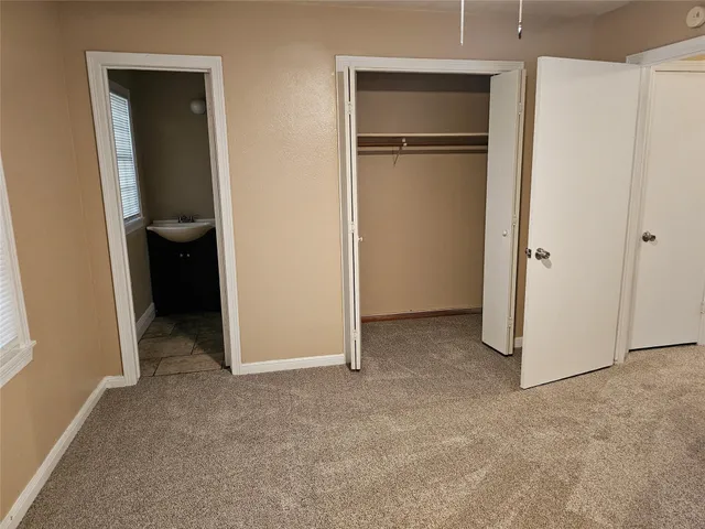 a view of an empty room with closet and wooden floor