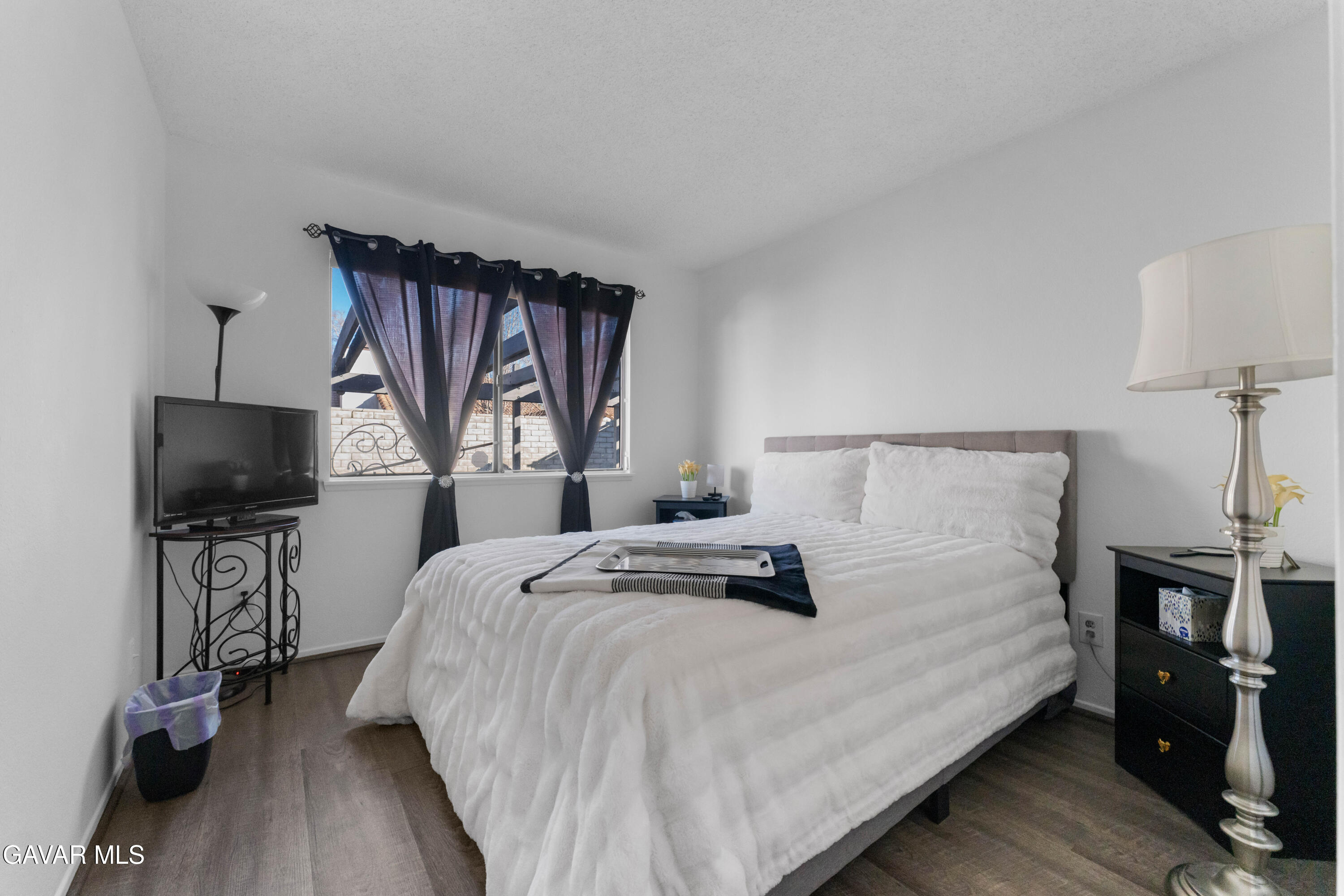 37720 Smoke Tree Street Palmdale, CA 93552 - Photo 10 of 17 a bedroom with a bed a tv and wooden floor