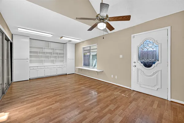 a view of a room with wooden floor and a ceiling fan