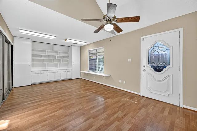 a view of a room with wooden floor and a ceiling fan