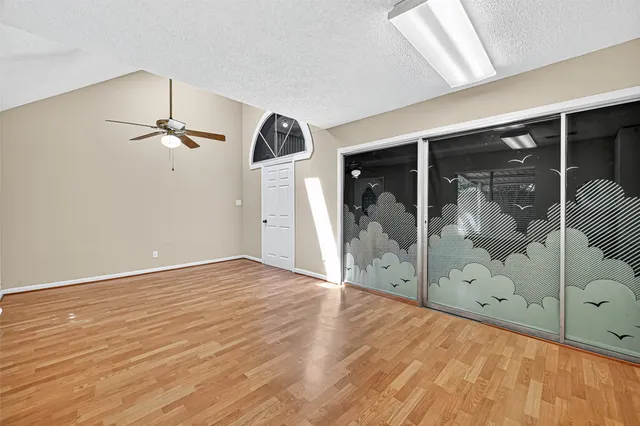 a view of empty room with wooden floor and fan