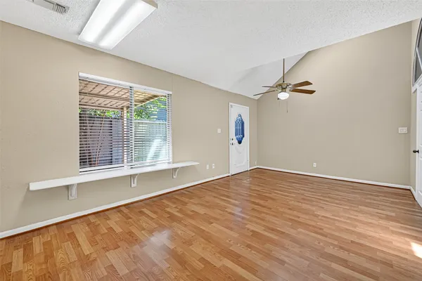 an empty room with wooden floor a fireplace a ceiling fan and windows