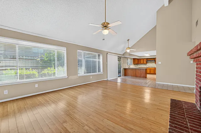 a view of an empty room with wooden floor fireplace and a window