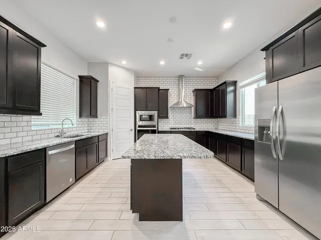 a large kitchen with a center island and stainless steel appliances