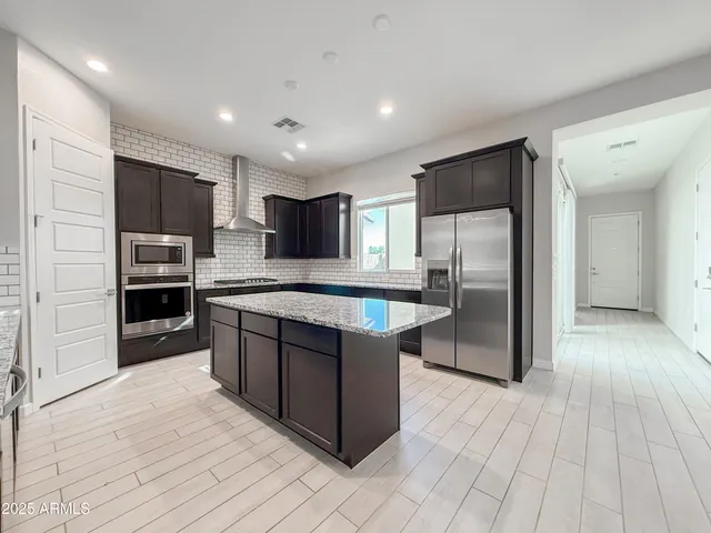 a kitchen with stainless steel appliances granite countertop a refrigerator and a stove top oven