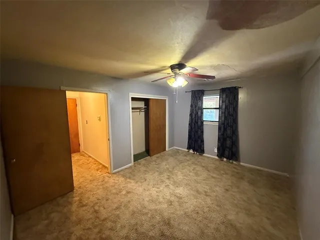a view of an empty room with a chandelier fan