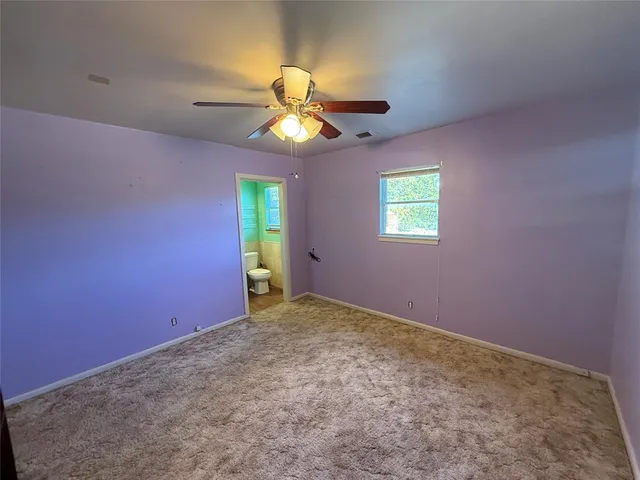 a view of an empty room with window and chandelier fan
