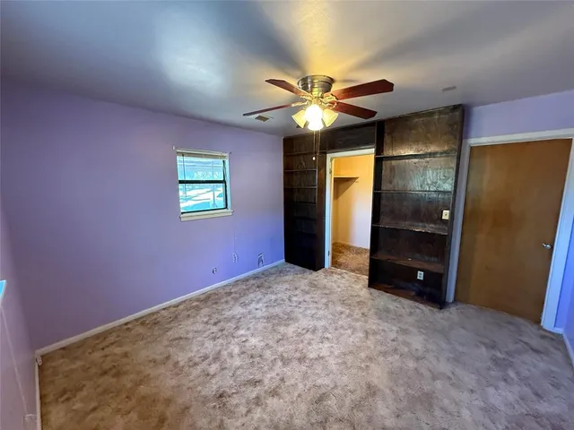 an empty room with closet and a chandelier fan