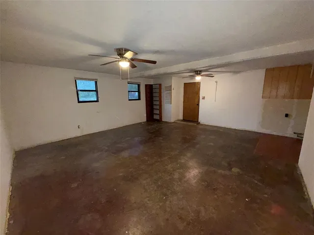 an empty room with ceiling fan and window