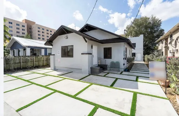 a view of a white house with a small yard and plants