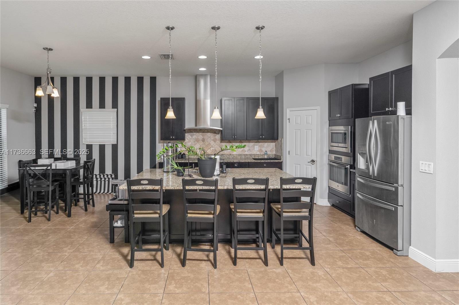 11436 Drifting Leaf Drive Riverview, FL 33579 - Photo 8 of 21 a kitchen with stainless steel appliances kitchen island granite countertop a refrigerator and a dining table