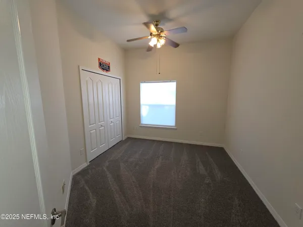 a view of an empty room and chandelier fan