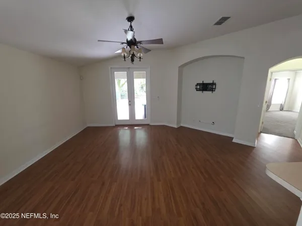 a view of an empty room with wooden floor and a window