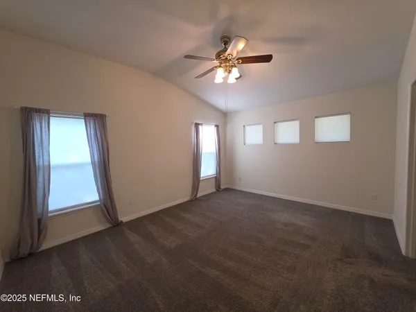a view of an empty room with window and chandelier fan