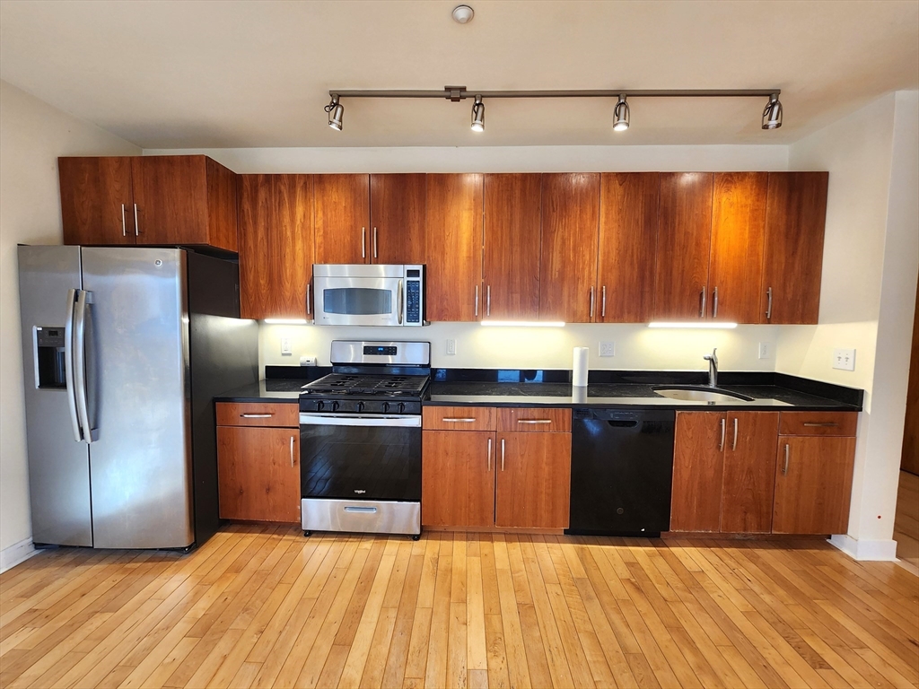 24 Bay State Road, Unit 11 Cambridge, MA 02138 - Photo 11 of 26 a kitchen with stainless steel appliances granite countertop a refrigerator a sink and wooden cabinets