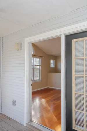 a view of an empty room with window and wooden floor