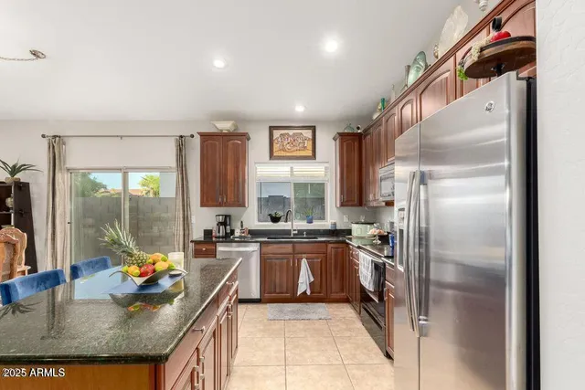 a kitchen with stainless steel appliances granite countertop a refrigerator a stove and a sink