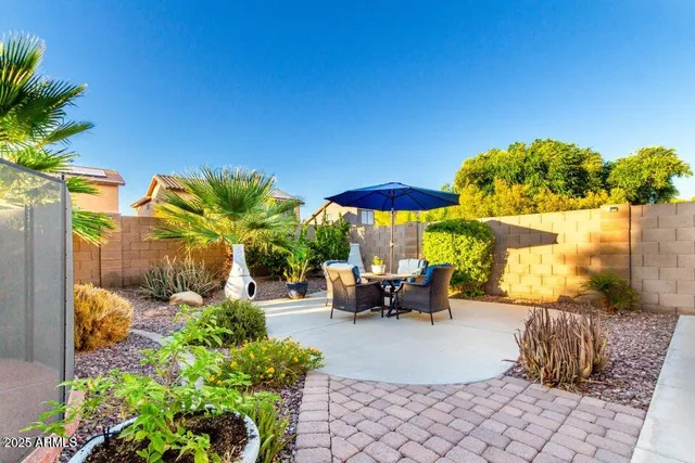 a view of a patio with table and chairs under an umbrella with potted plants