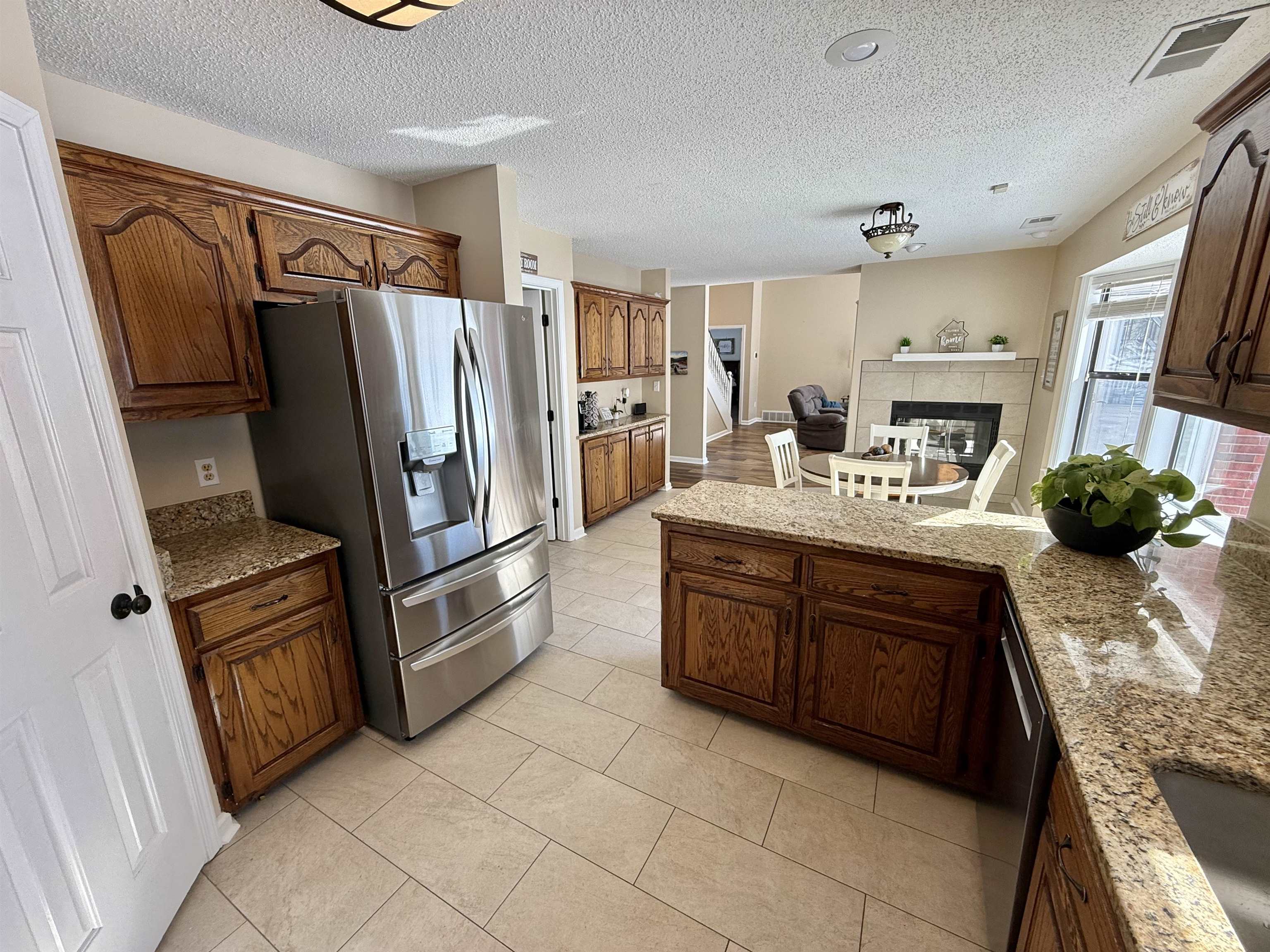 3415 Chambers Road Millington, TN 38053 - Photo 10 of 27 Kitchen featuring stainless steel appliances, a tile fireplace, a peninsula, light stone countertops, and a textured ceiling