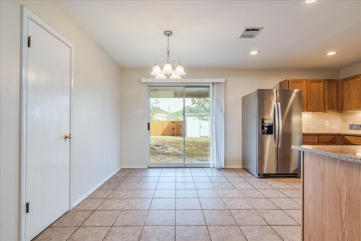 267 Carolyns Way Buda, TX 78610 - Photo 14 of 31 a view of a refrigerator in kitchen and an empty room with windows